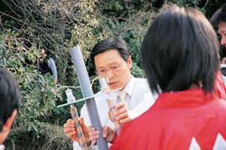 写真：学生から小水力発電機の説明を受ける市長