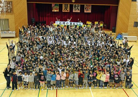 写真：学校の体育館でカメラに向かって手を挙げる生徒達