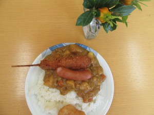 写真：机の上にあるお皿に串カツとウインナーをトッピングした石榑の里カレーがある様子