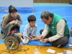 写真：民生委員さんが企画する実験コーナー参加している親子の様子