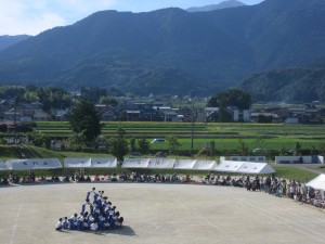 写真：竜ヶ岳を背に組立体操「頂・竜ヶ岳」を演じる児童