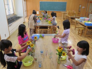 写真:花あそび会で花盛りとなった紫陽花を中心に初夏の草花を飾る児童達