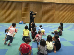 写真:黒のマントと帽子に身を包んだ先生が、繰り出す手品に大喜びの児童達