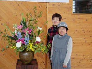 写真:花を生けた地域の先生二人と舞台横に飾られた花