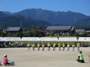 写真：石榑小4年生の児童達による一輪車を駆使したパフォーマンス「風神車輪」。4月から取り組んだ成果が発揮され一糸乱ず隊列を組んだ風神たちがグランド狭しと駆け巡る様子