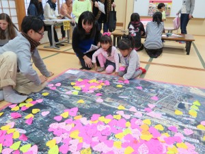 写真：名古屋大学の学生によるワークショップ「アイいしぐれマッピング」でハート形に切り取られた紙を画用紙に貼る児童達