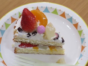 写真：生クリームの上にイチゴやみかんが乗っているショートケーキ