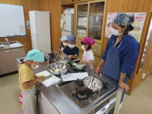 写真：お菓子を作る下ごしらえのために包丁を使う児童を見守る保護者