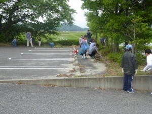 写真：曇りの中、石榑小学校の駐車場付近の草抜きをする様子