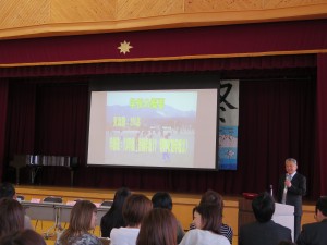 写真:育友会総会でプロジェクターを使って学校方針を参加者に説明する校長先生
