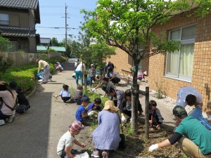 写真：石榑小学校校内にある遊歩道こもれびの小経の草抜きをする児童と保護者ら