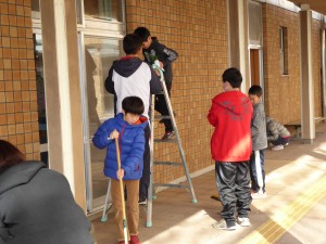 写真:児童たちが協力して脚立を使って校舎の高い所の窓を掃除する様子